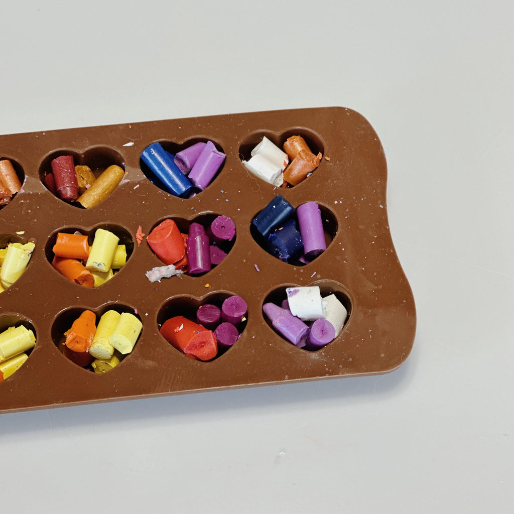 Silicone heart mold filled with broken crayon pieces ready to be melted into new crayons by us!