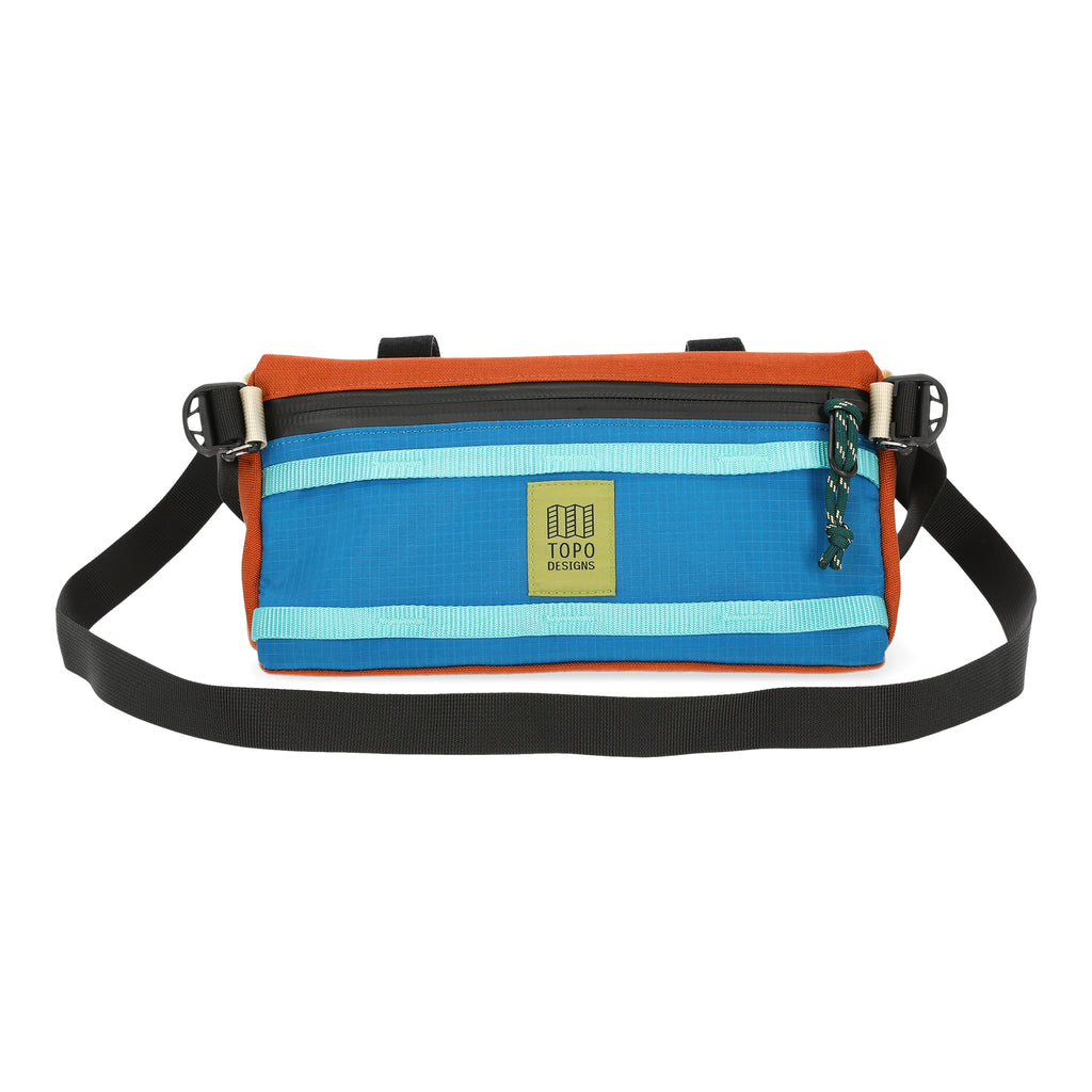 Topo Designs Bike Bag Mountain in Bone White/Blue. Bag is triangle shaped with multiple colors of webbing and nylon and a waterproof zipper. Removable black shoulder strap allows you to take the bag with you wherever you go. Shown on a white background.