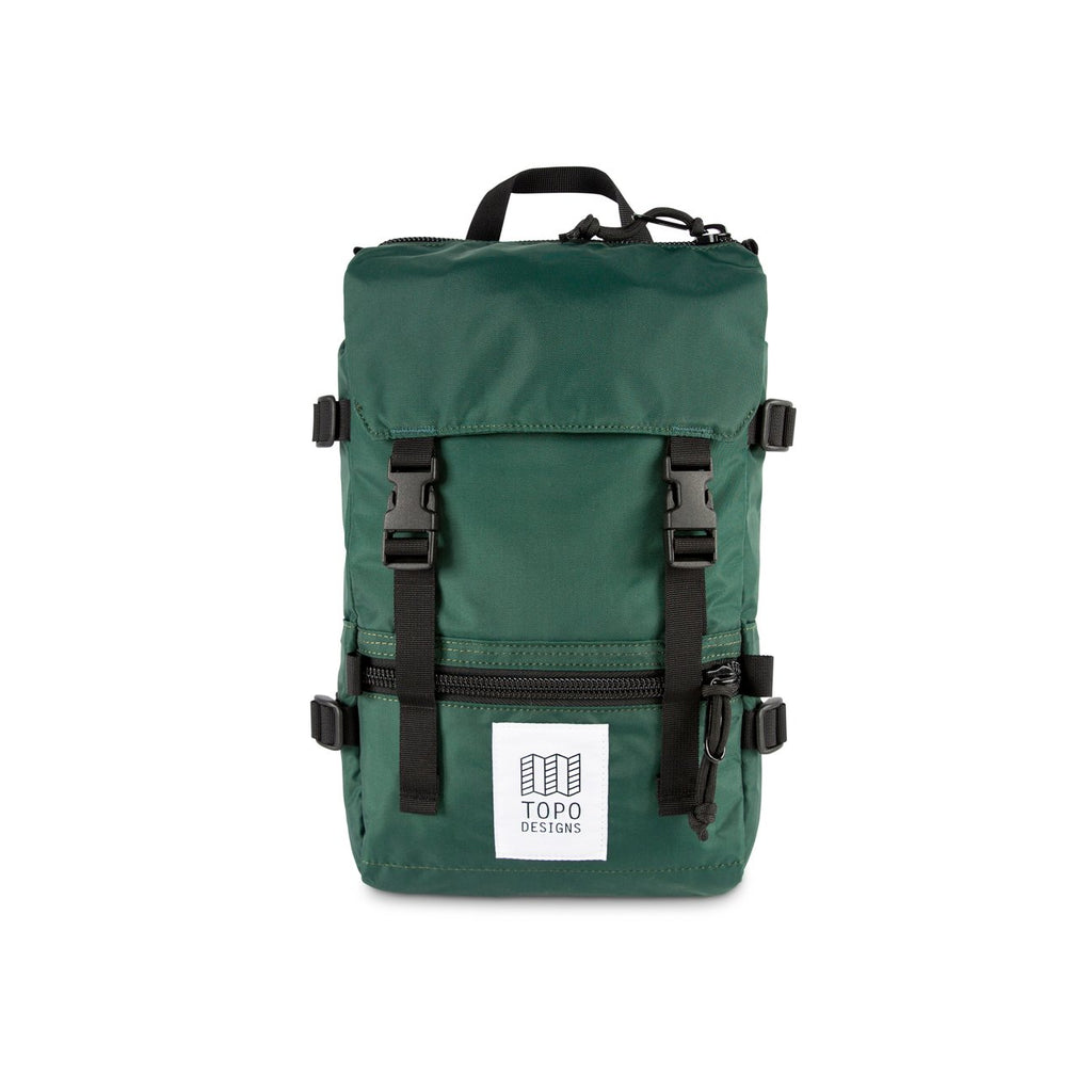 Topo Designs Mini Rover backpack in Forest green nylon with black nylon straps, black buckles, black zippers and white and black Topo Designs label on the front pocket. Item is shown on a white background. 