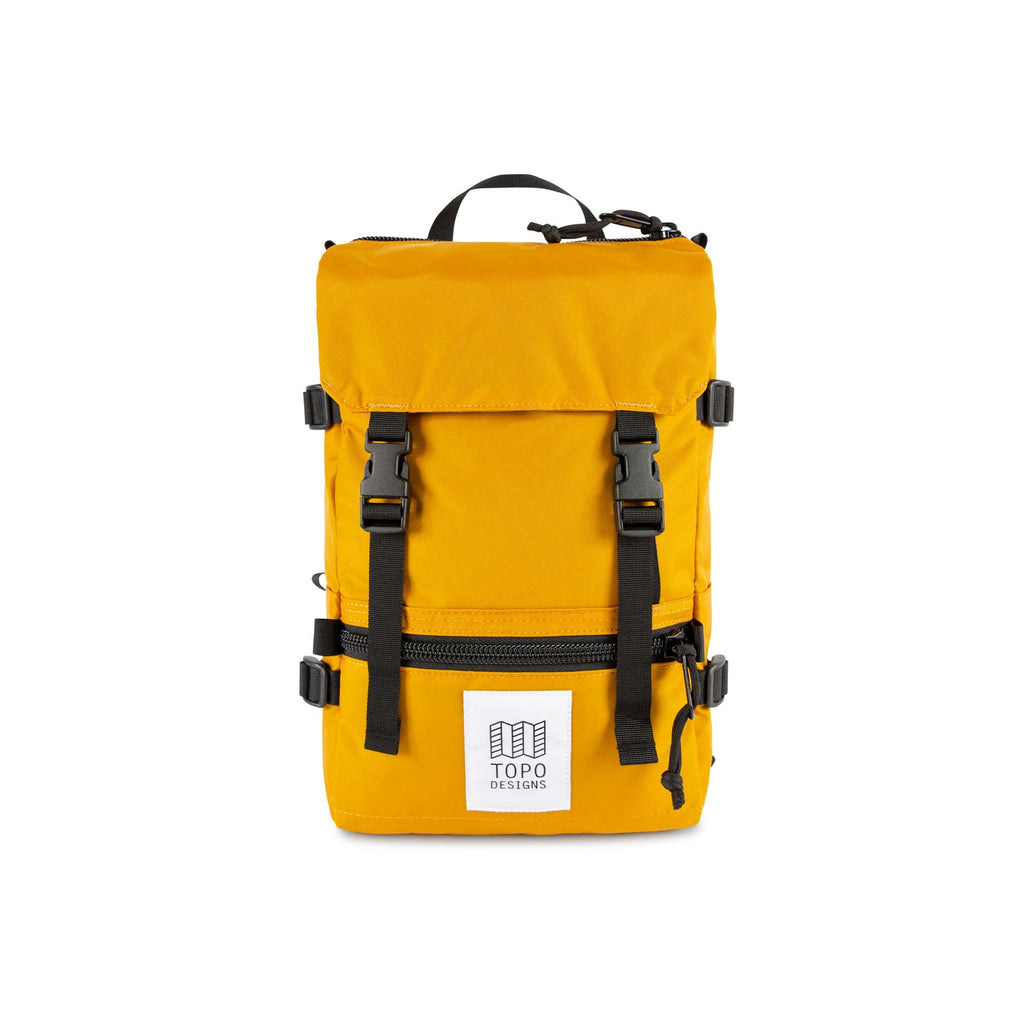 Topo Designs Mini Rover backpack in Mustard nylon with black nylon straps, black buckles, black zippers and white and black Topo Designs label on the front pocket. Item is shown on a white background.